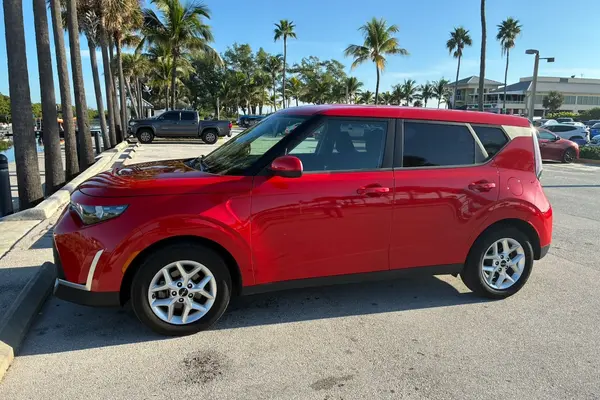 Red 2024 Kia Soul in profile from the driver's side, showing its boxy shape and silver alloy wheels