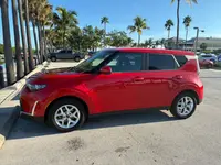 Red 2024 Kia Soul in profile from the driver's side, showing its boxy shape and silver alloy wheels