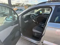 2023 Volkswagen Taos with the driver's door open, showing the grey cloth driver's seat, steering wheel, and dashboard, at a marina