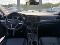 2024 Volkswagen Jetta front interior showing the steering wheel, center touchscreen, climate dials, automatic shifter, and black seats